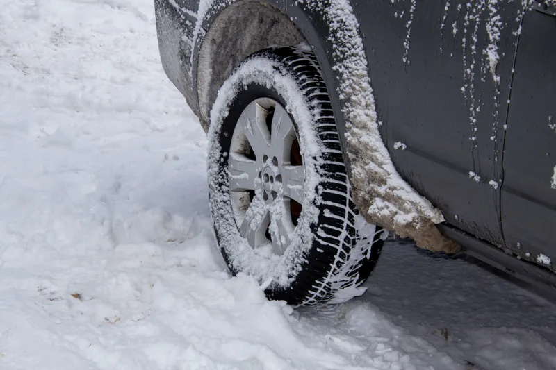 Road salt and slush caked around the wheel and arch of a car in winter