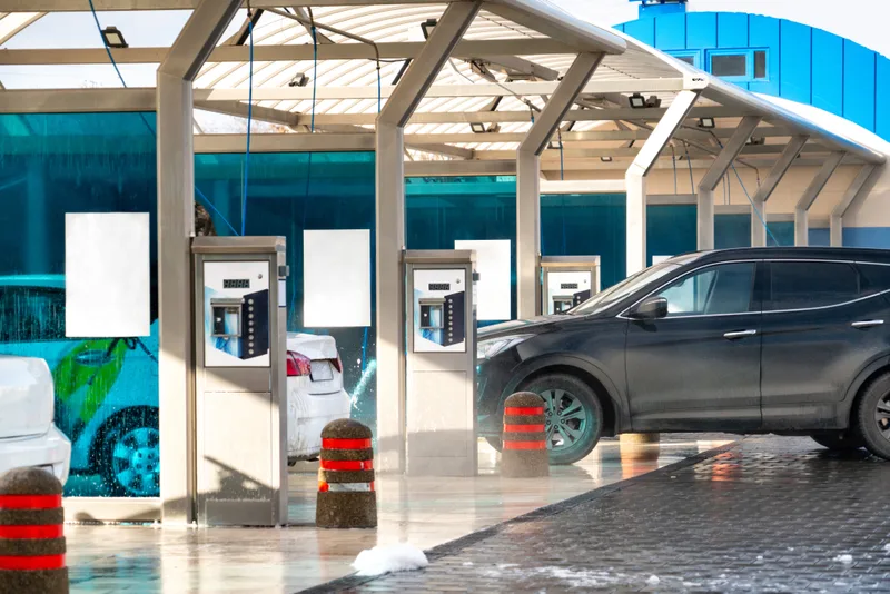 Open self-serve wash bays with pay stations and a car parked in the first bay