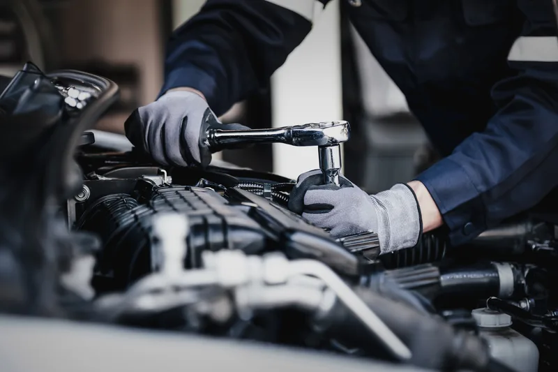 A Ridgepoint technician in work gloves torquing an engine component with a ratchet