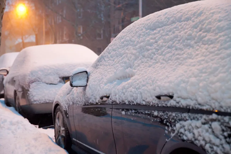 Cars parked on a street under a thick layer of fresh snow