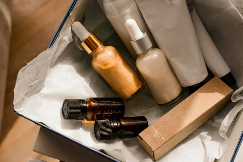 A take-home skincare box with dropper serums and amber vials nested in tissue paper