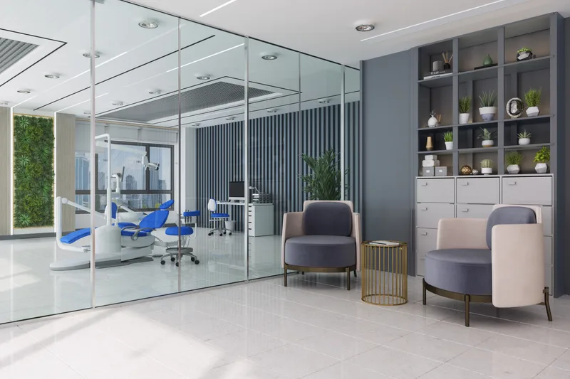 The clinic lounge — upholstered chairs beside a glass-walled treatment room with plants and open shelving