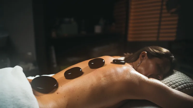 Smooth heated basalt stones resting along a client's back in low, warm candlelight
