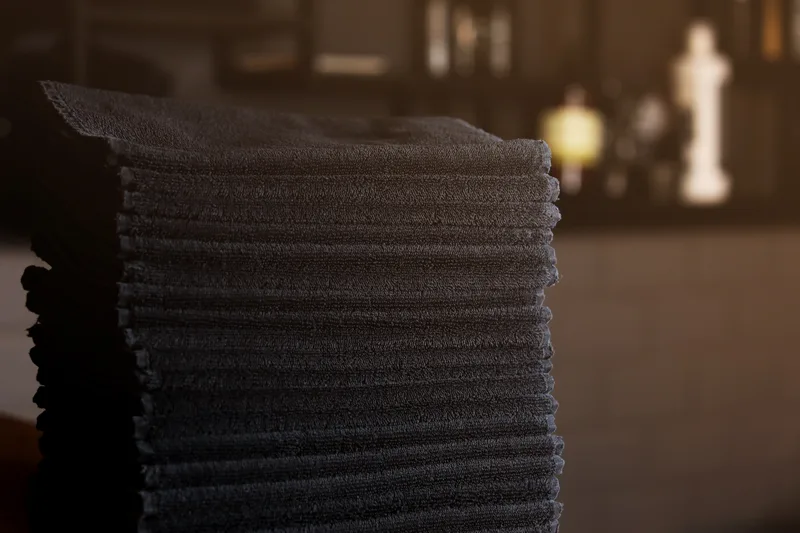 Stack of folded black towels on a shelf in a barbershop