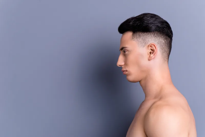 Side profile of a young man with a high fade and a slicked-back top