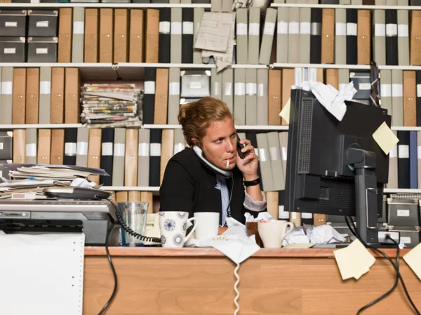 An admissions counselor wearing a headset speaking with a caller at a desk in a treatment center office