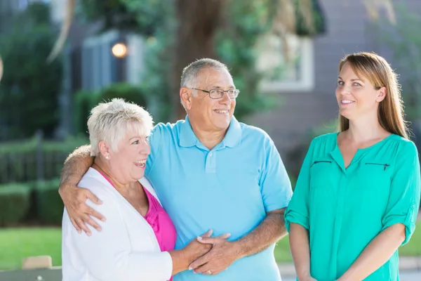 A senior-living advisor walking an adult daughter and her elderly mother through an assisted-living community during a tour