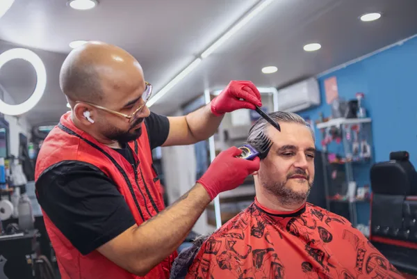 A barber finishing a fresh fade for a seated client in a modern barbershop
