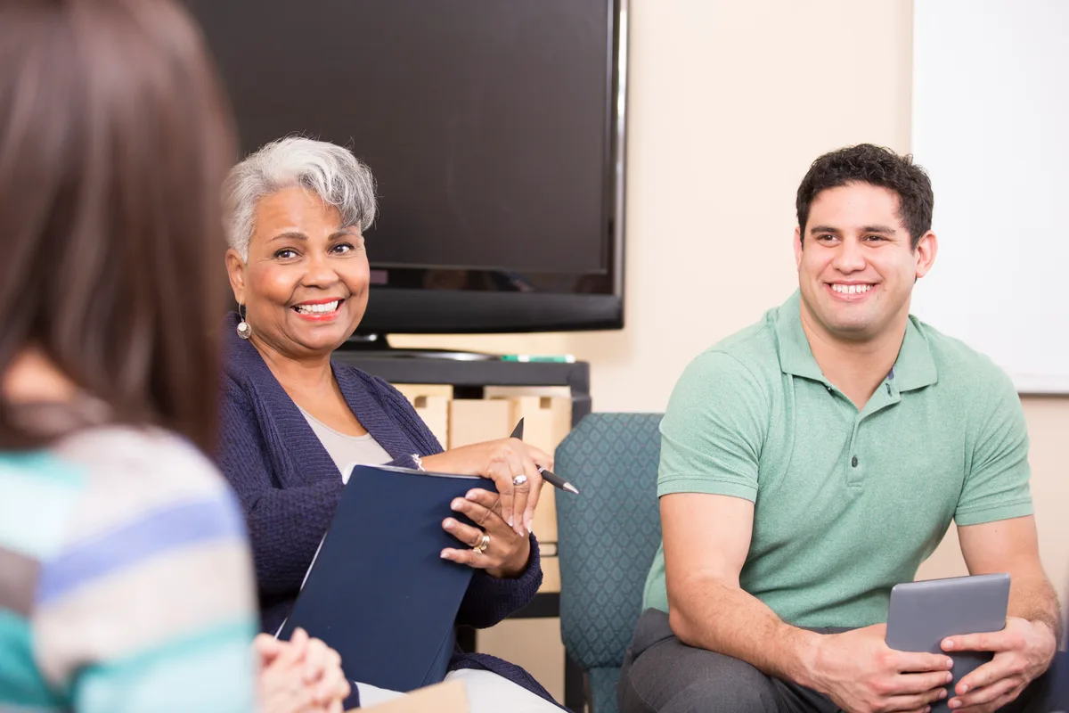 An admissions counselor at a treatment center meeting with a family in a bright, calm office