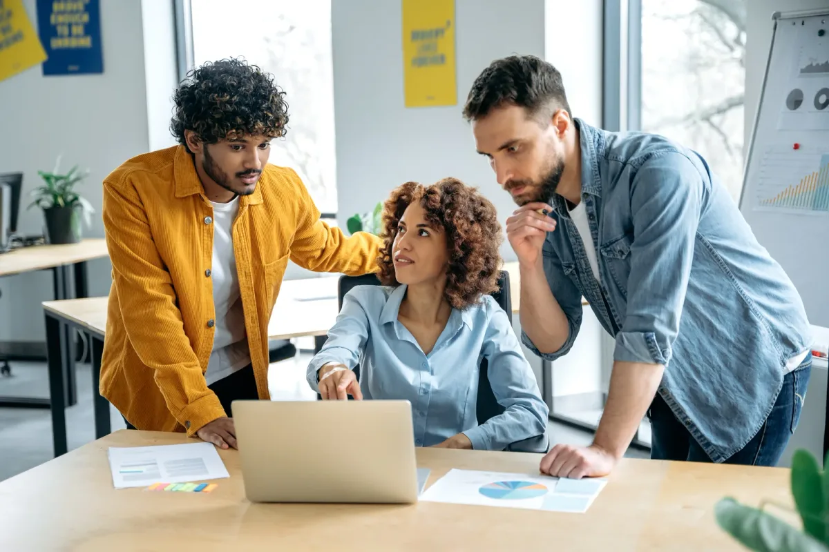 A small startup team reviewing product and marketing metrics on a laptop