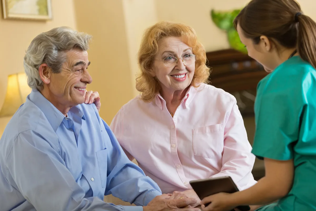Assisted-living director walking an adult daughter and her mother through a bright community common area during a tour
