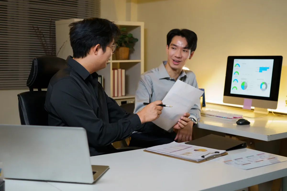 An analyst reviewing a business intelligence dashboard with several charts on a wide monitor