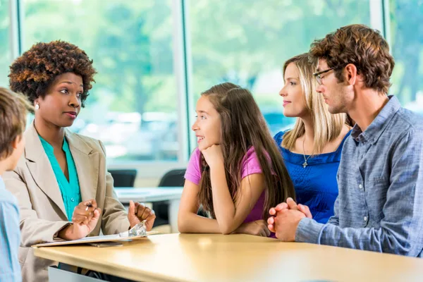 A college admissions consultant reviewing an application plan with a parent and their high school student