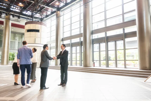 Commercial real estate broker meeting a client in a downtown office building lobby