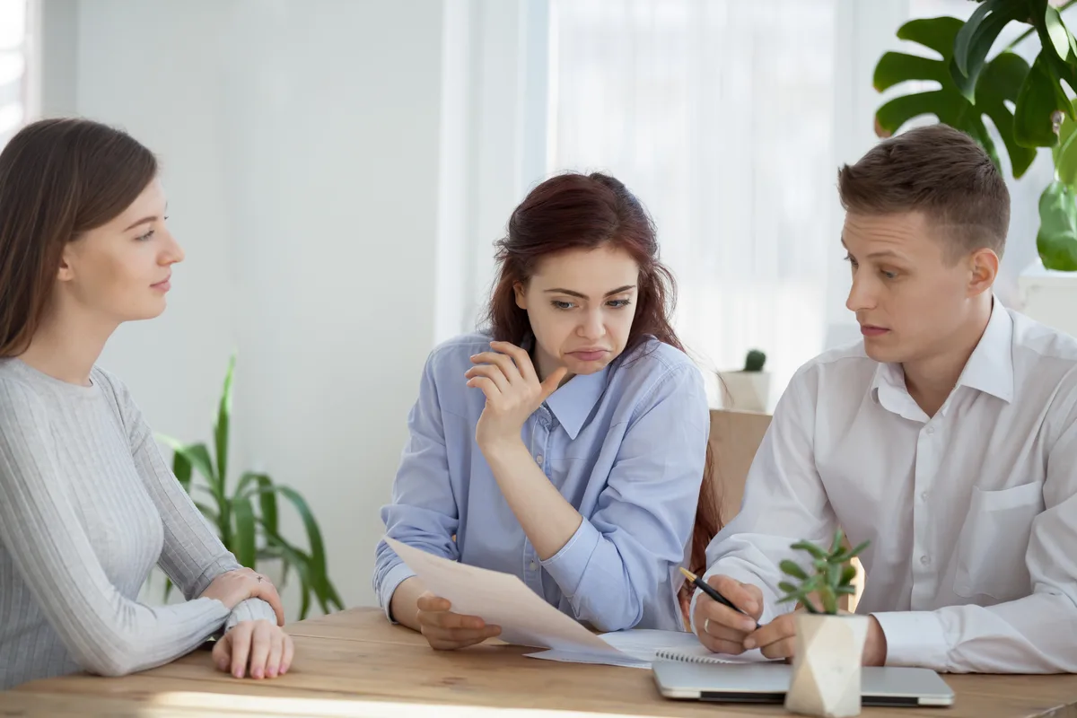 A debt relief specialist reviewing a repayment plan with a concerned couple across a desk