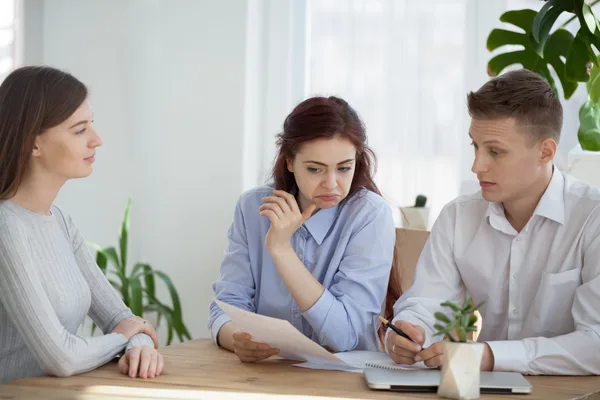 A debt relief specialist reviewing a repayment plan with a concerned couple across a desk