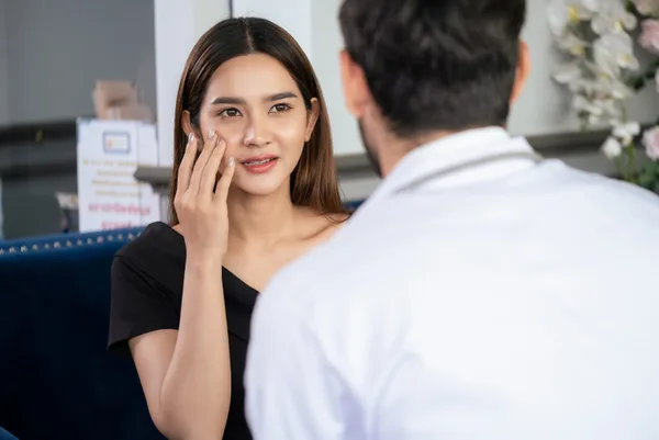 A board-certified dermatologist greeting a patient at the front desk of a modern skin clinic
