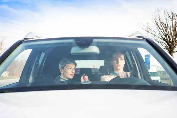 A certified driving instructor coaching a teenage student in a dual-control training car