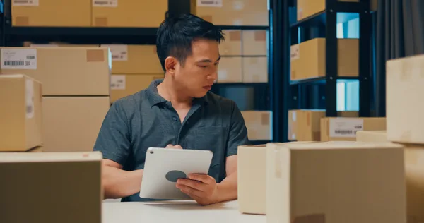 Online store owner reviewing orders and marketing performance on a laptop beside packed shipping boxes
