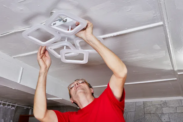 A licensed electrician wiring a residential electrical panel during a service call