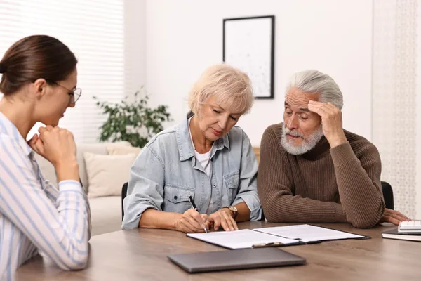 Estate planning lawyer reviewing will and trust documents across a desk with an older couple in a law office