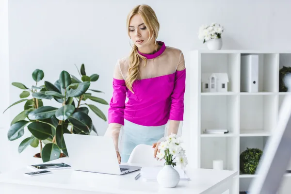 Event planner reviewing a client portfolio and inquiry list on a laptop in a bright studio