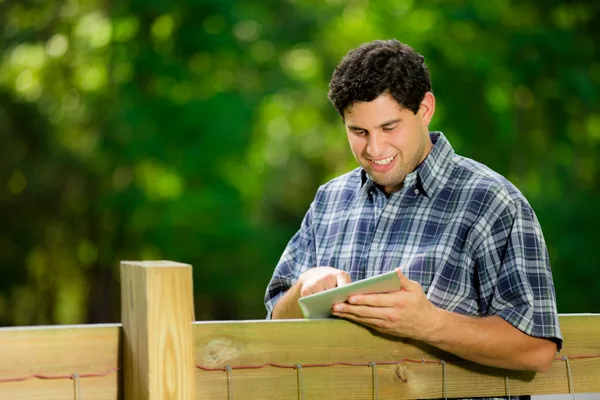 Fencing contractor reviewing an estimate on a tablet at a residential backyard job site
