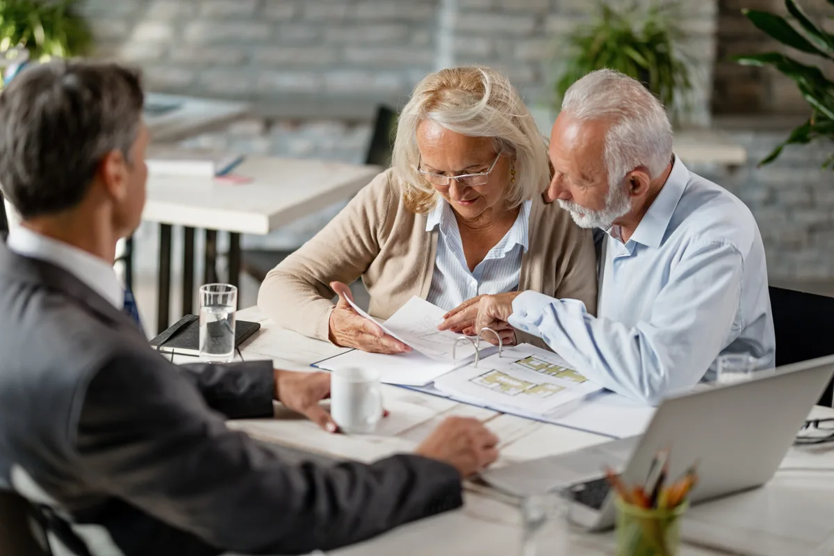 A financial advisor reviewing a retirement plan with a couple across a desk in a bright office