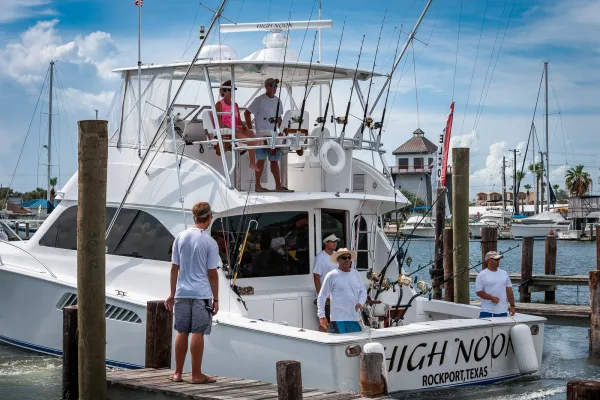 Captain and anglers holding a fresh catch on the deck of a charter fishing boat