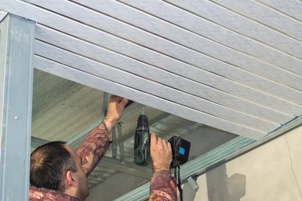Garage door technician installing a new residential overhead door on a suburban home