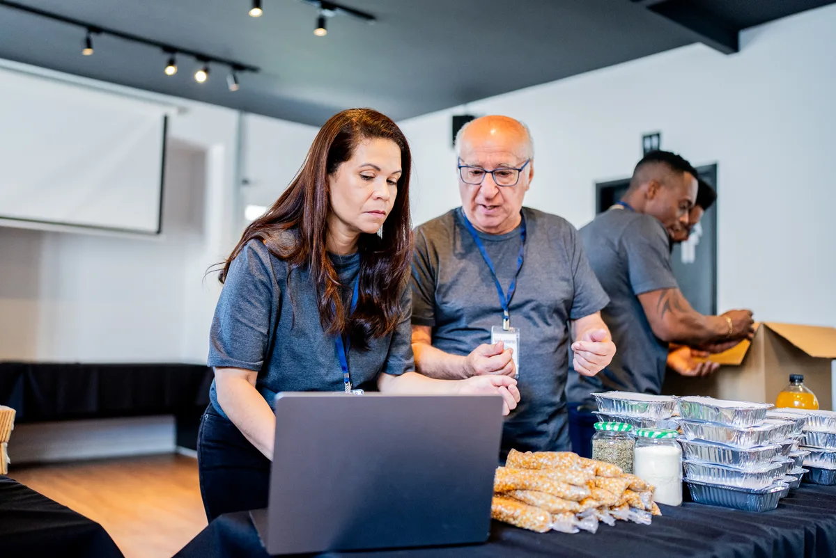Gym owner and a marketing consultant reviewing membership and lead data on a laptop at the studio front desk