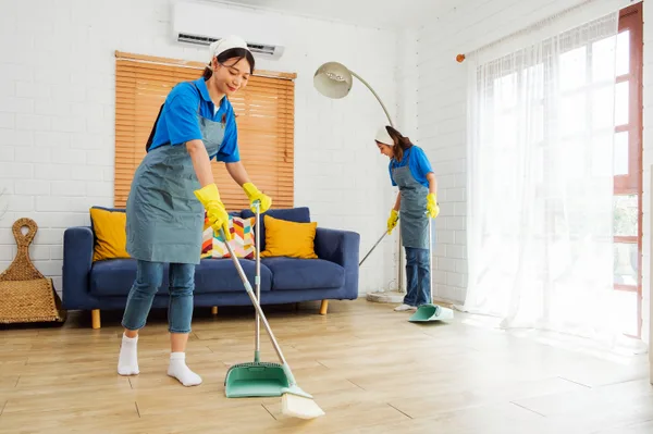 A uniformed professional cleaner wiping down surfaces in a bright, modern residential living room