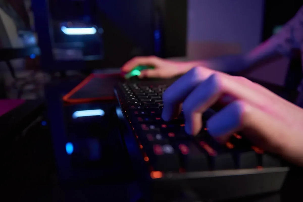 Indie game developers at a small studio desk reviewing their Steam wishlist numbers on a laptop
