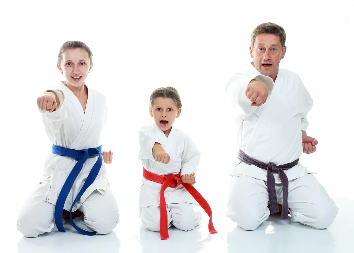 A martial arts instructor leading a kids karate class on the mats while parents watch from the side