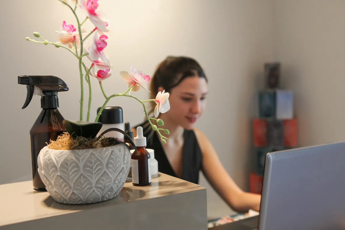 Day spa owner reviewing booking and marketing performance on a laptop at the reception desk