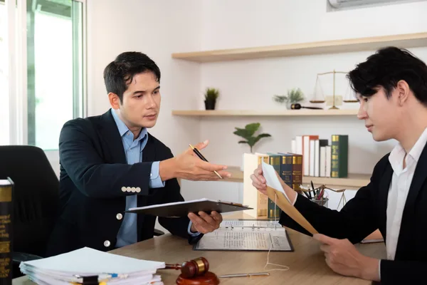 A medical malpractice attorney reviewing case documents with a client across a desk in a law office