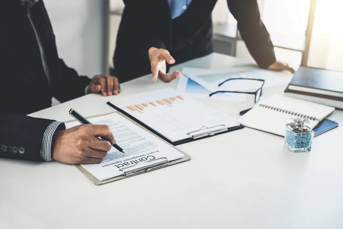 M&A attorney reviewing a purchase agreement with a business owner across a conference table