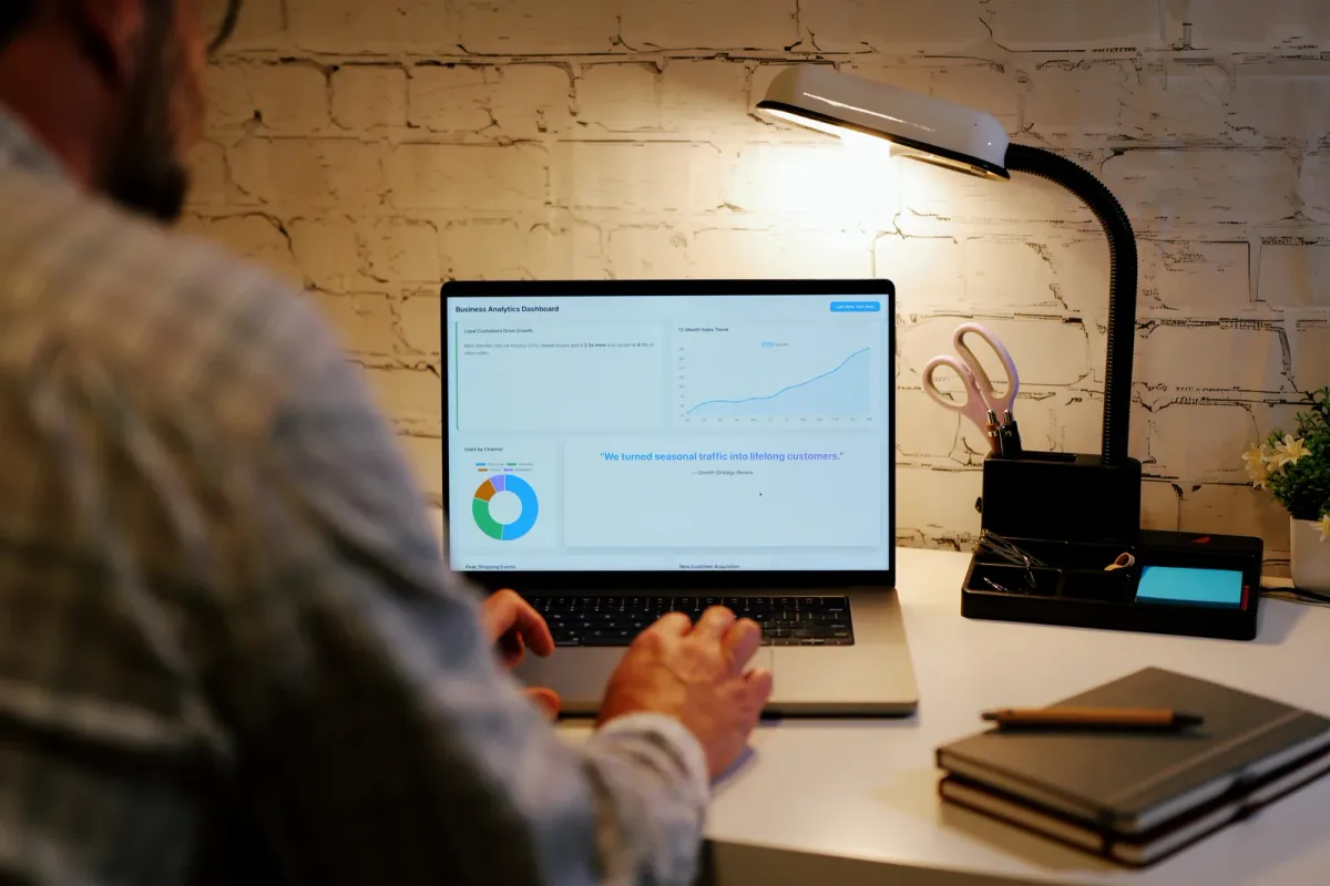 Solo software founder reviewing trial signups and revenue charts on a laptop at a home desk