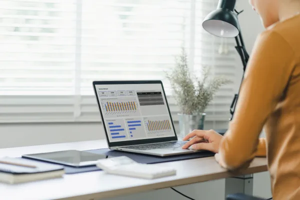 Online course creator reviewing student enrollment and completion data on a laptop at a desk