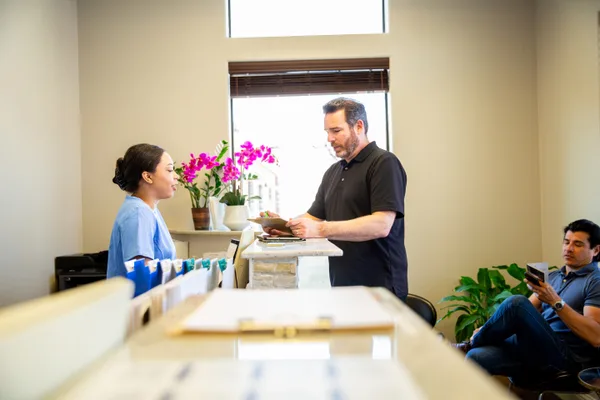 Physical therapy clinic owner reviewing the patient schedule with a colleague at the front desk
