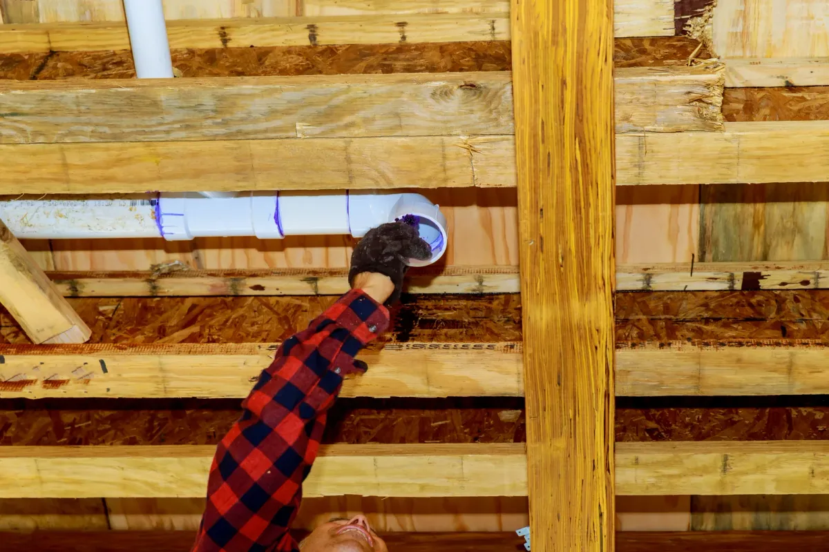 Radon mitigation technician installing a vent pipe system in a home basement