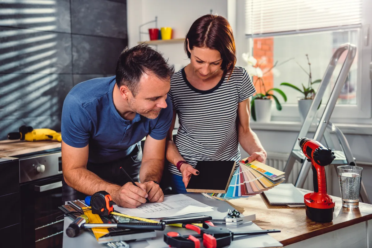 Two remodeling contractors reviewing renovation plans at a job site before meeting a homeowner