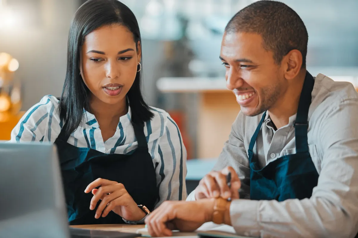 A restaurant manager entering an order on a point of sale terminal at a busy counter