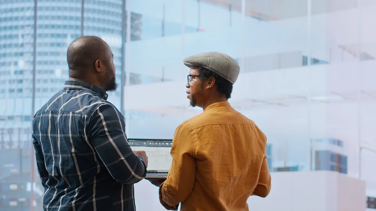 Two SaaS founders reviewing a marketing analytics dashboard together at a laptop in a modern office