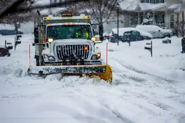 A snow plow truck clearing a commercial parking lot during a winter storm
