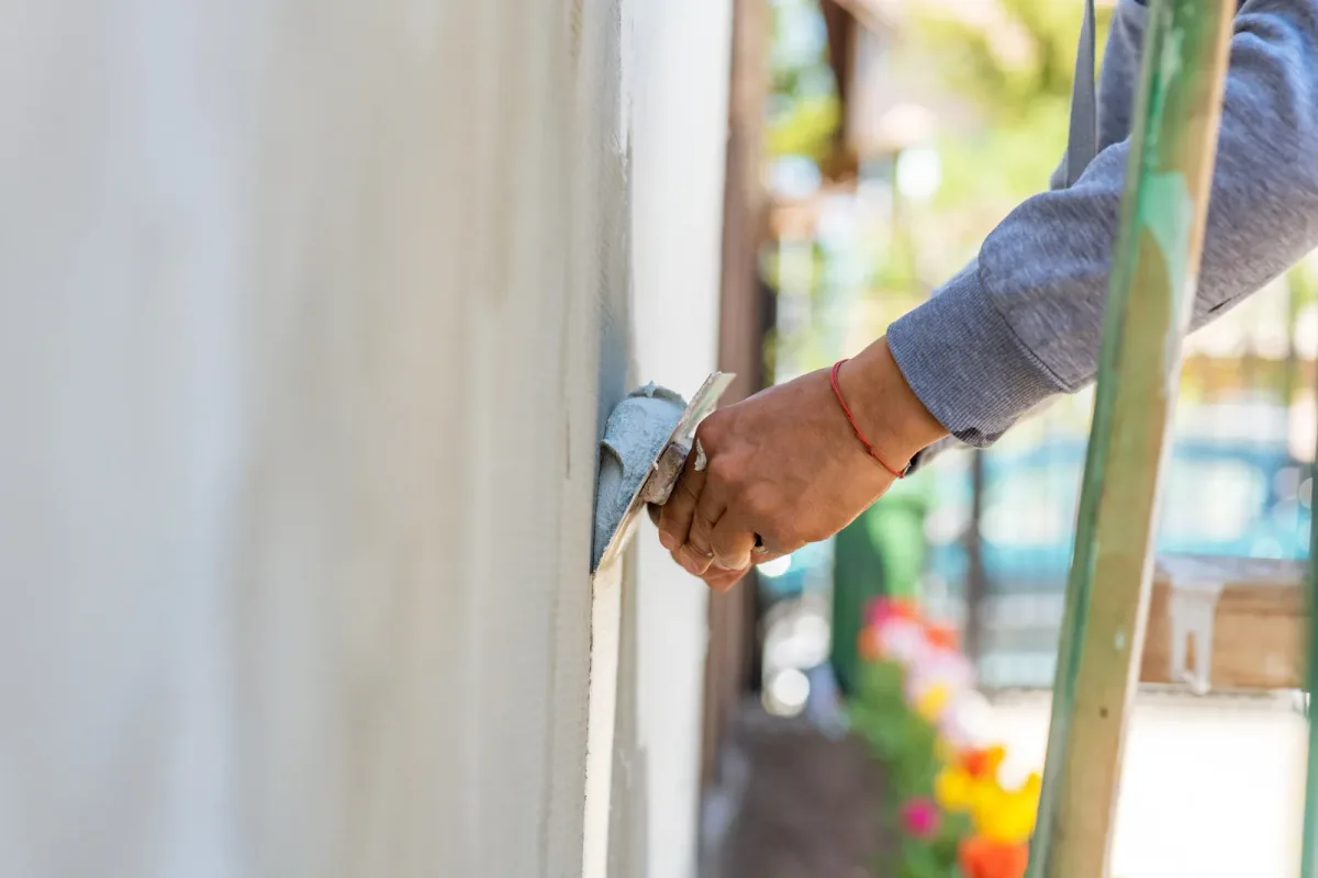 Stucco contractor troweling a fresh textured finish coat onto an exterior wall during a repair job