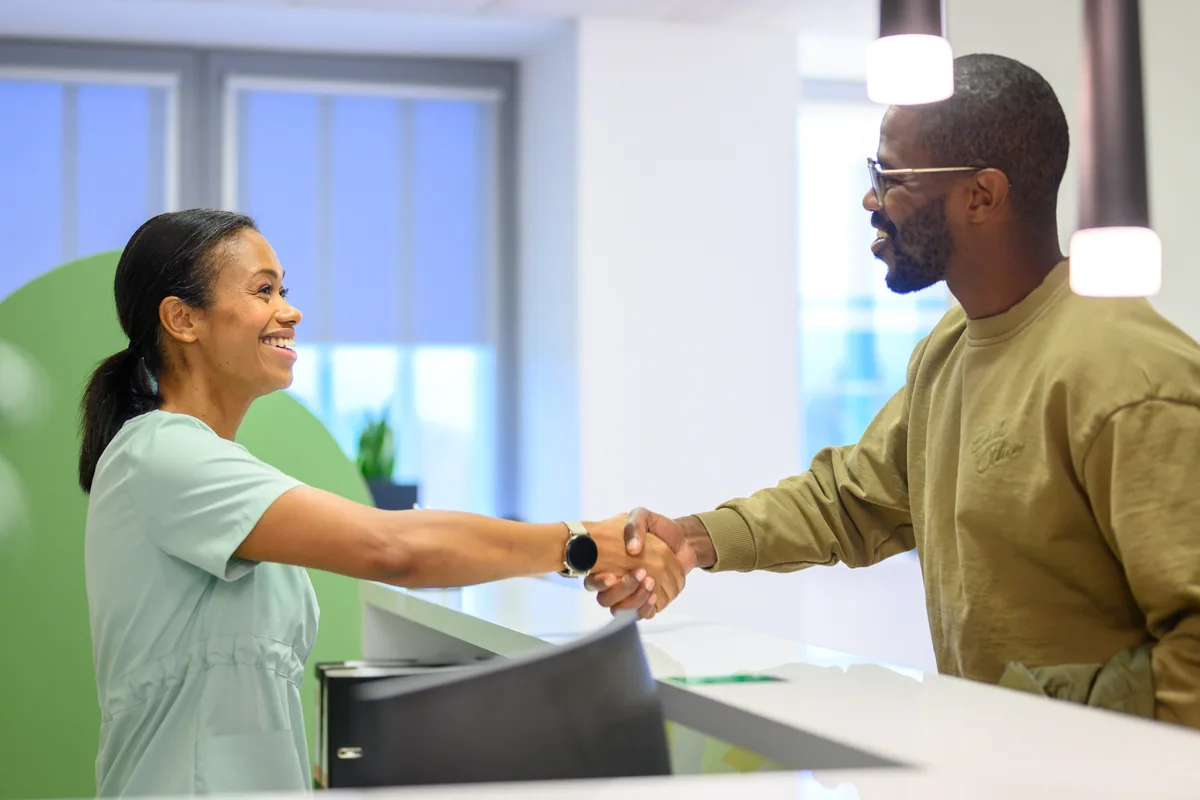 Front-desk staff at an urgent care clinic checking in a patient at the reception counter