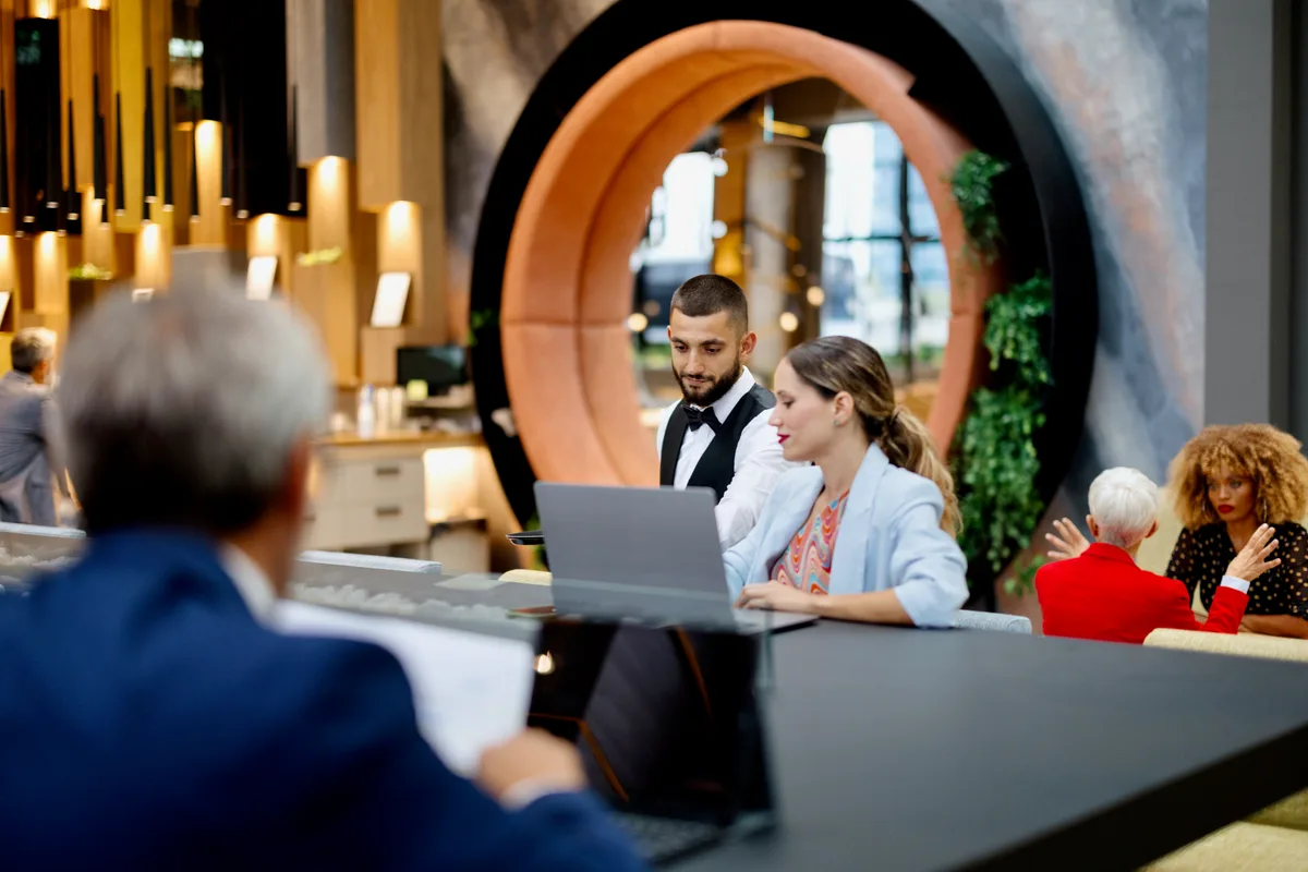 Wedding venue owner reviewing a marketing plan on a laptop inside a bright, set event space