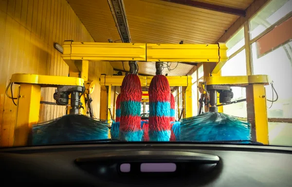 A car moving through an express tunnel car wash with soap foam and cloth brushes