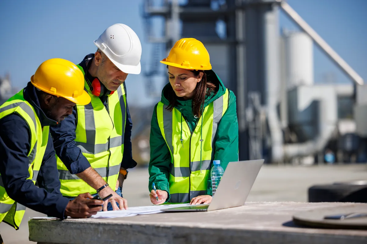 Commercial construction project manager and team reviewing blueprints on an active building site